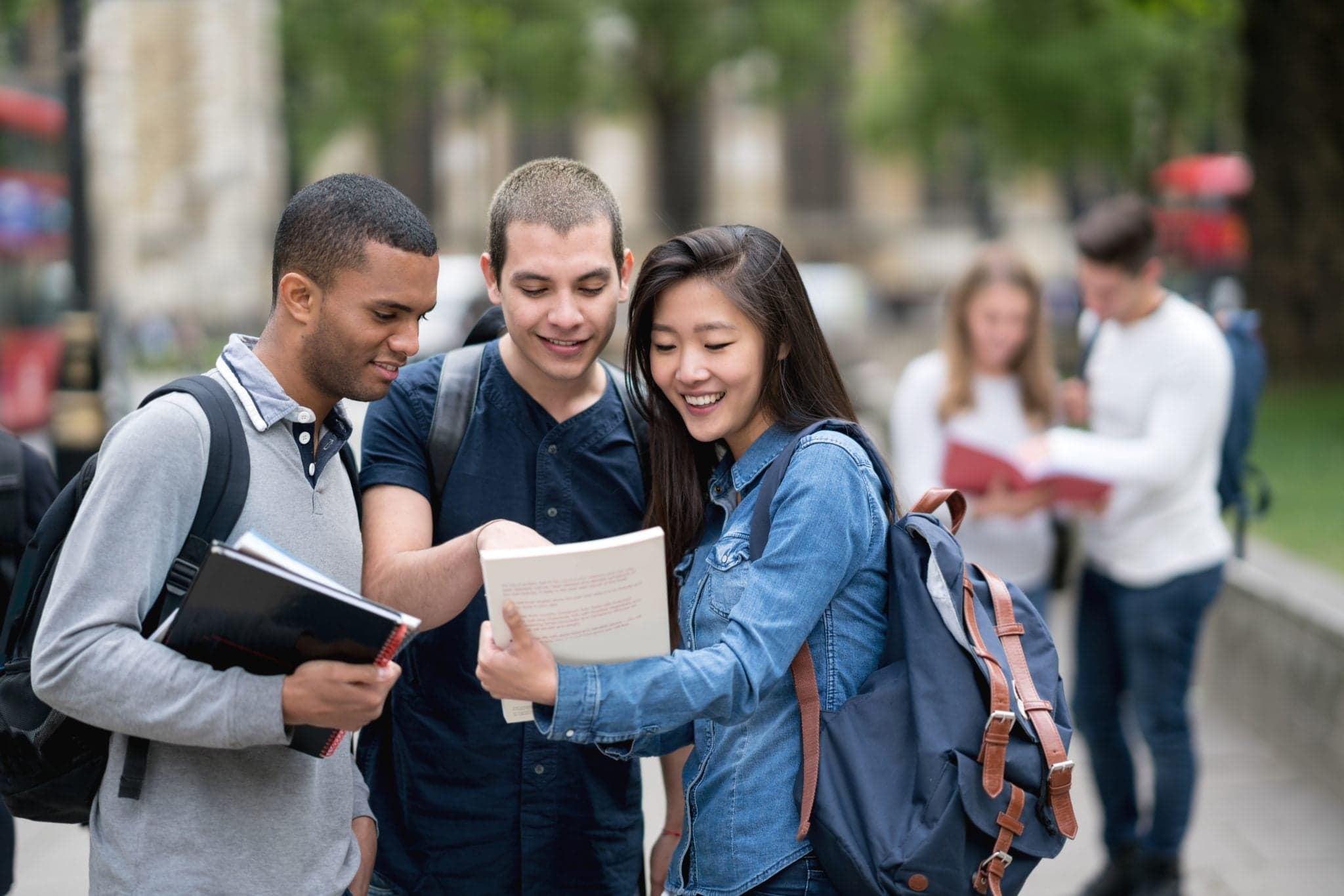 Image of Portrait of a happy multi-ethnic group of students studying outdoors and smiling - education concepts