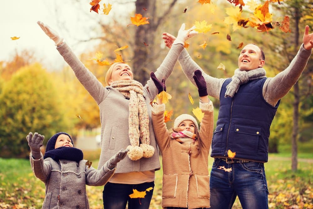 Picture of happy family playing with autumn leaves in park