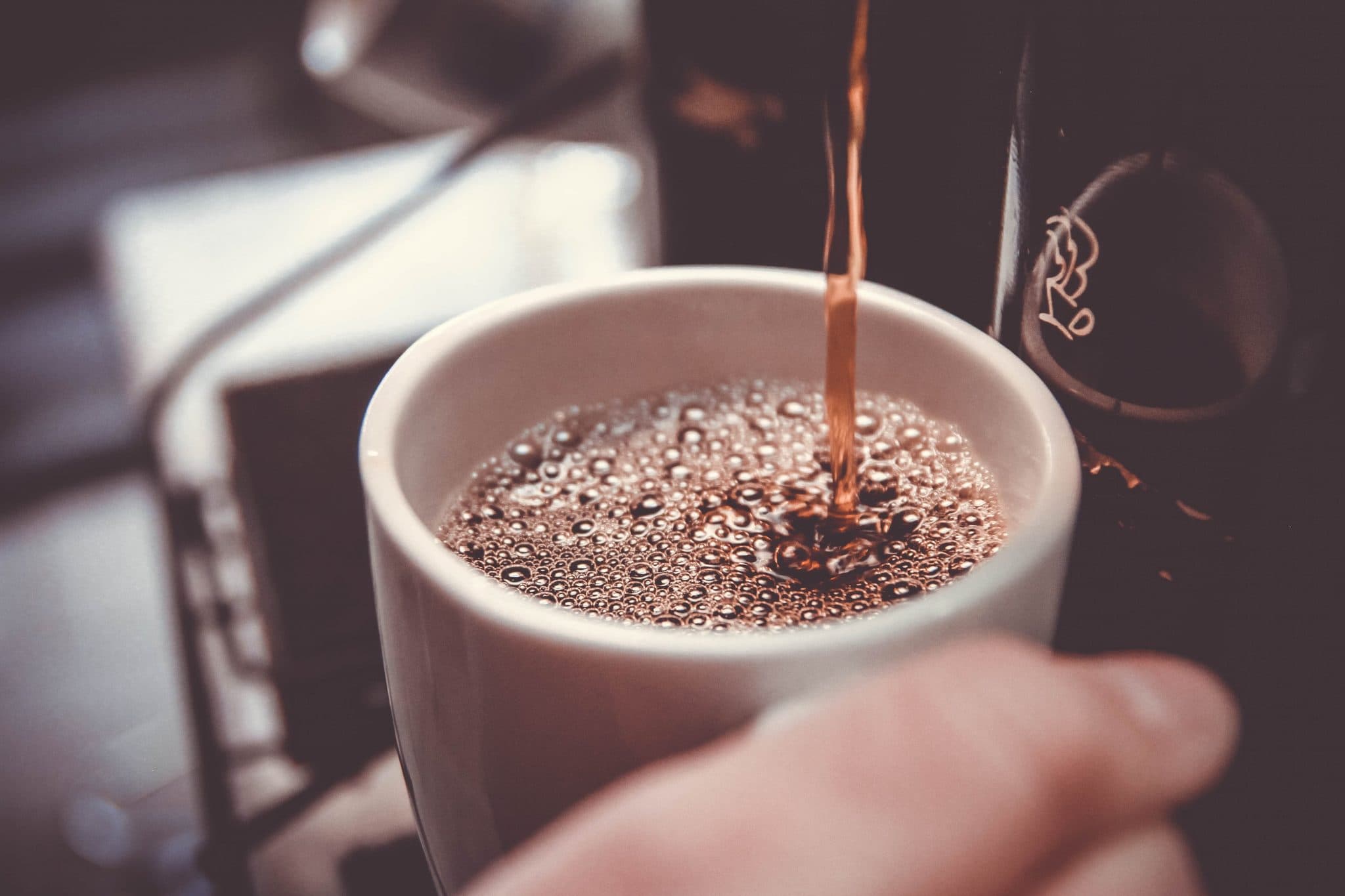 person filling up cup with coffee