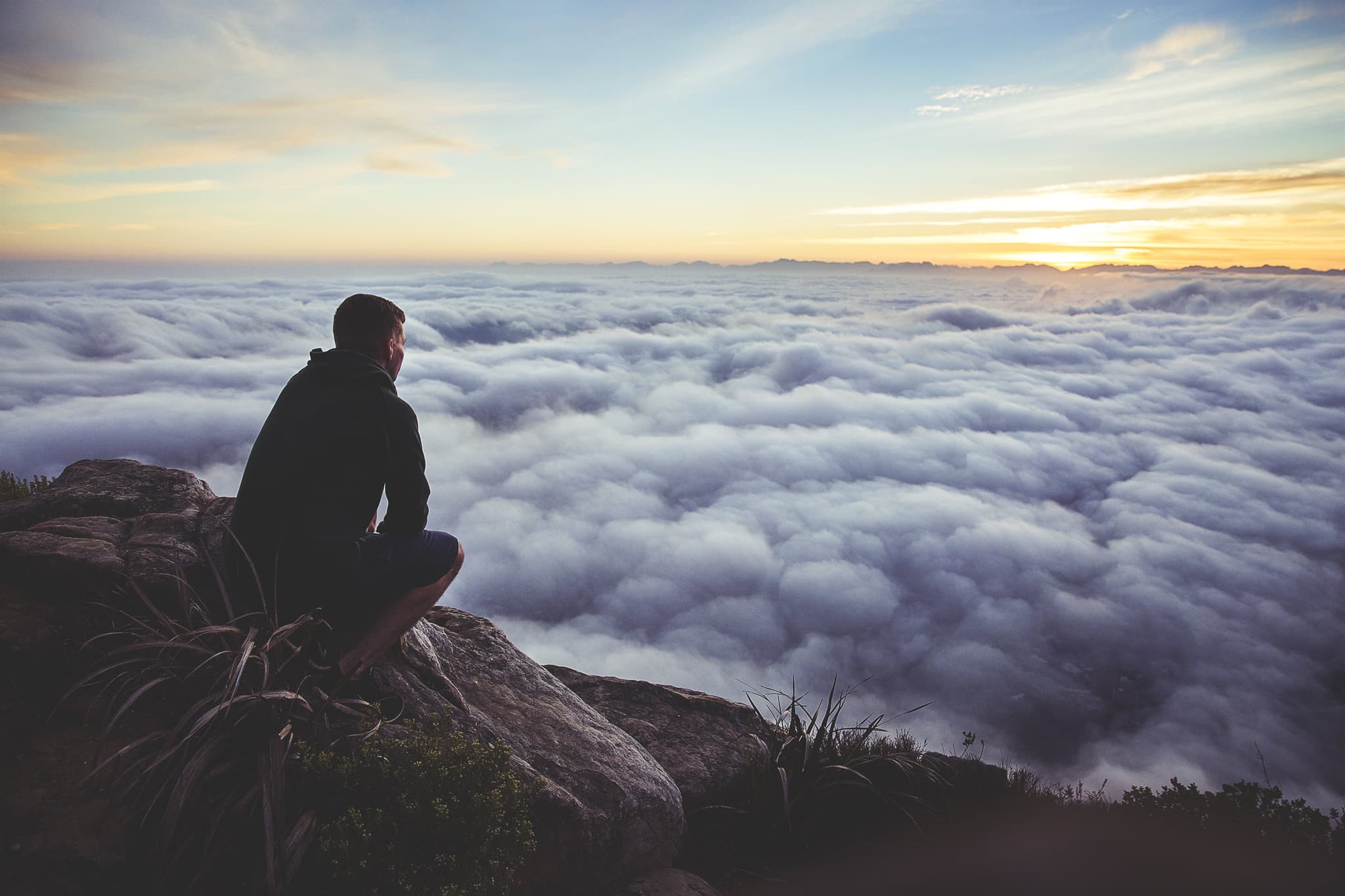 man admiring scenery - view above the clouds at sunset