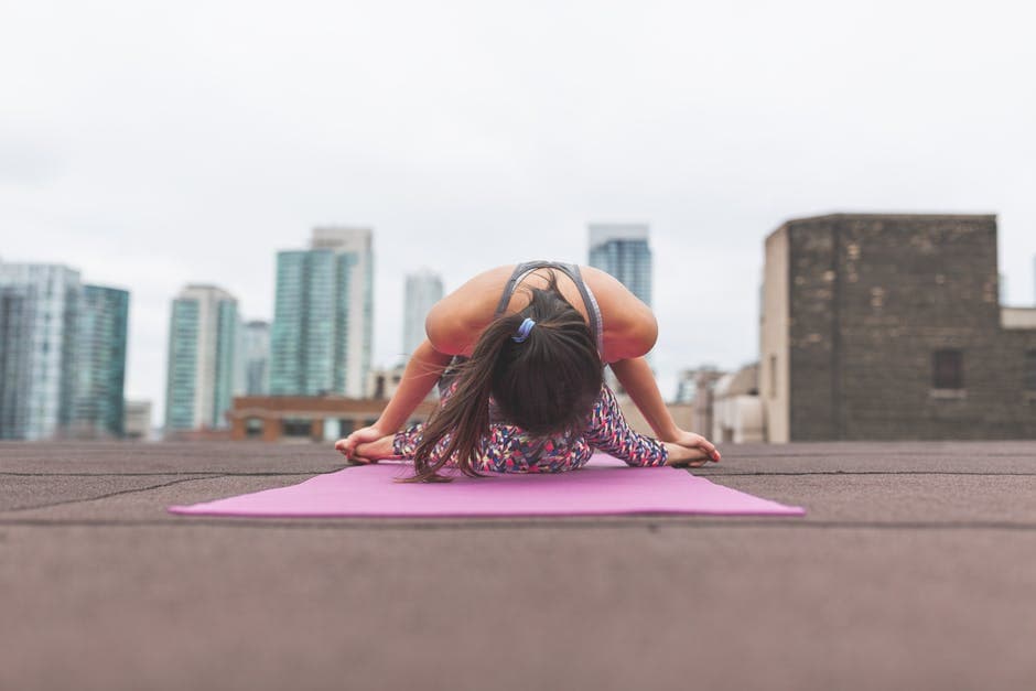 Picture of woman stretching on yoga mat on top of building in city