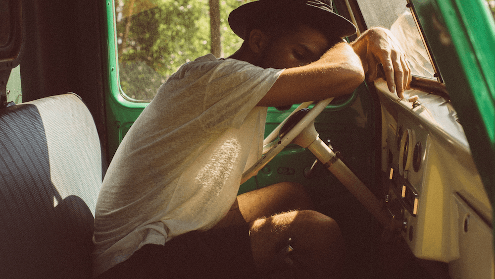 Picture of man sleeping in car in jungle