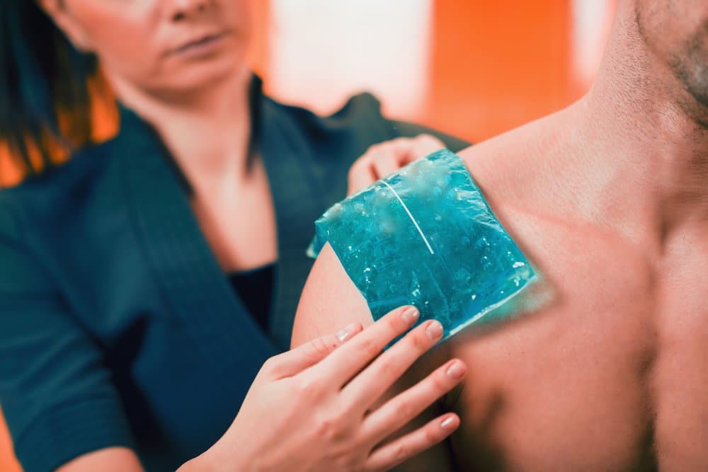 Holding the blue ice pack on the painful shoulder.