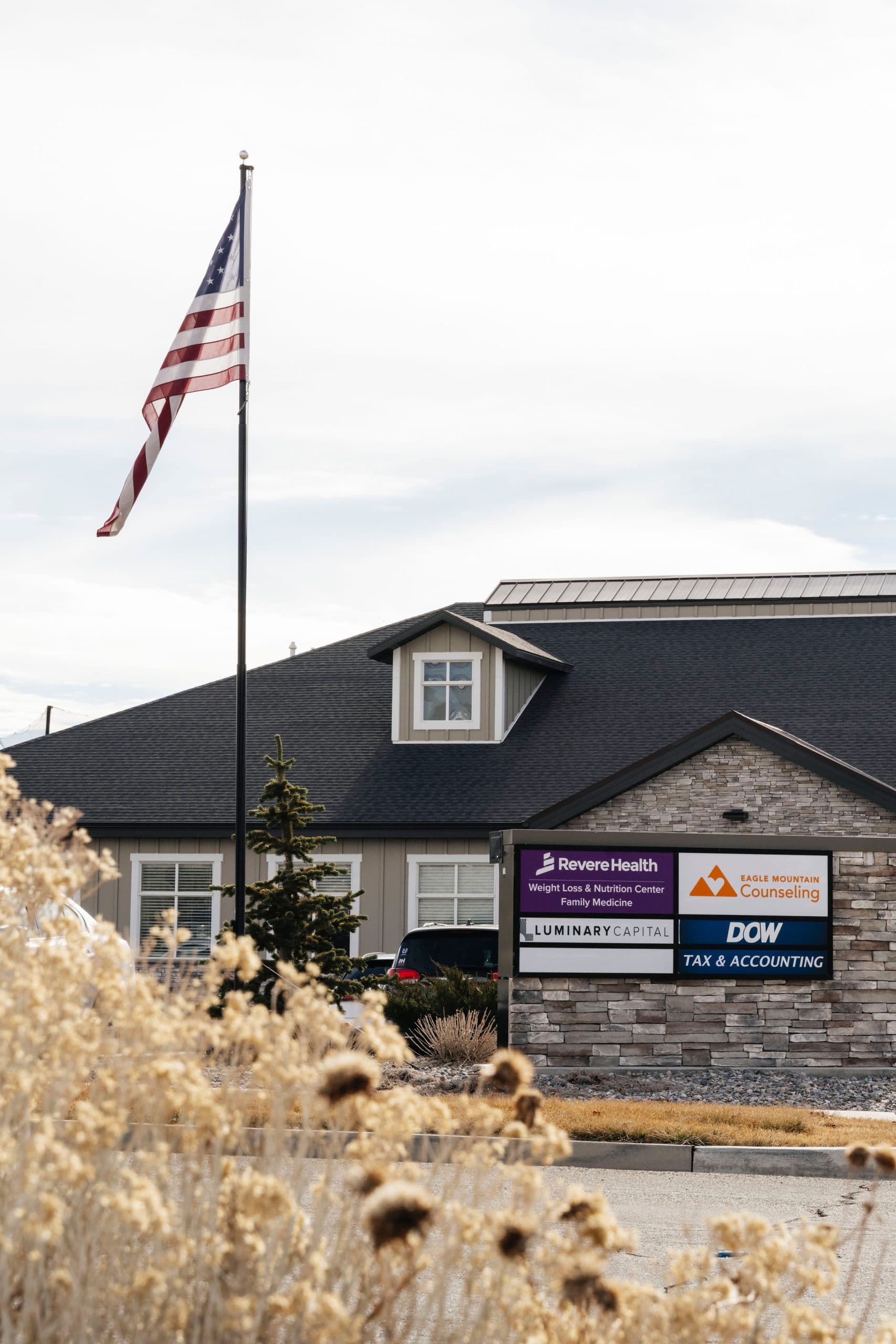 Close-up of building signage and American flag marking the entrance to Revere Health's specialty care clinics.