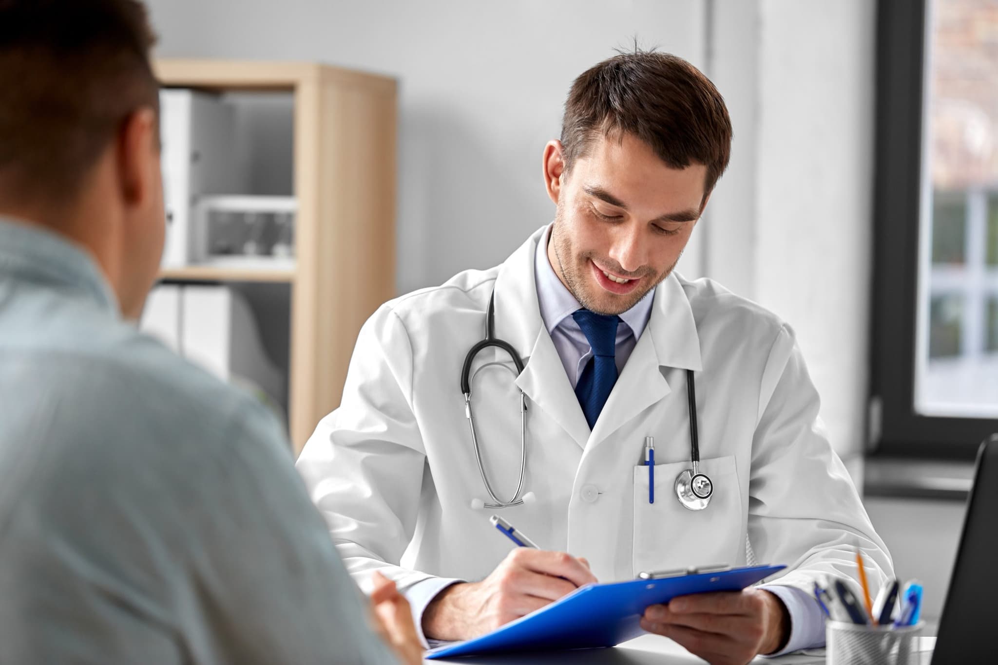 doctor with clipboard and male patient at hospital