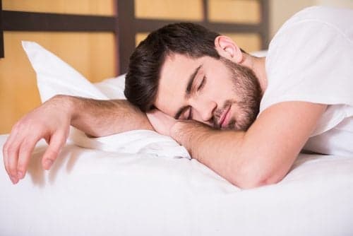 Close-up of young man is sleeping on bed.