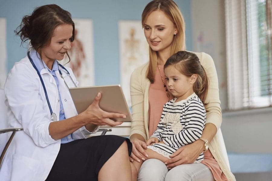 Picture of doctor showing ipad results to mother and child