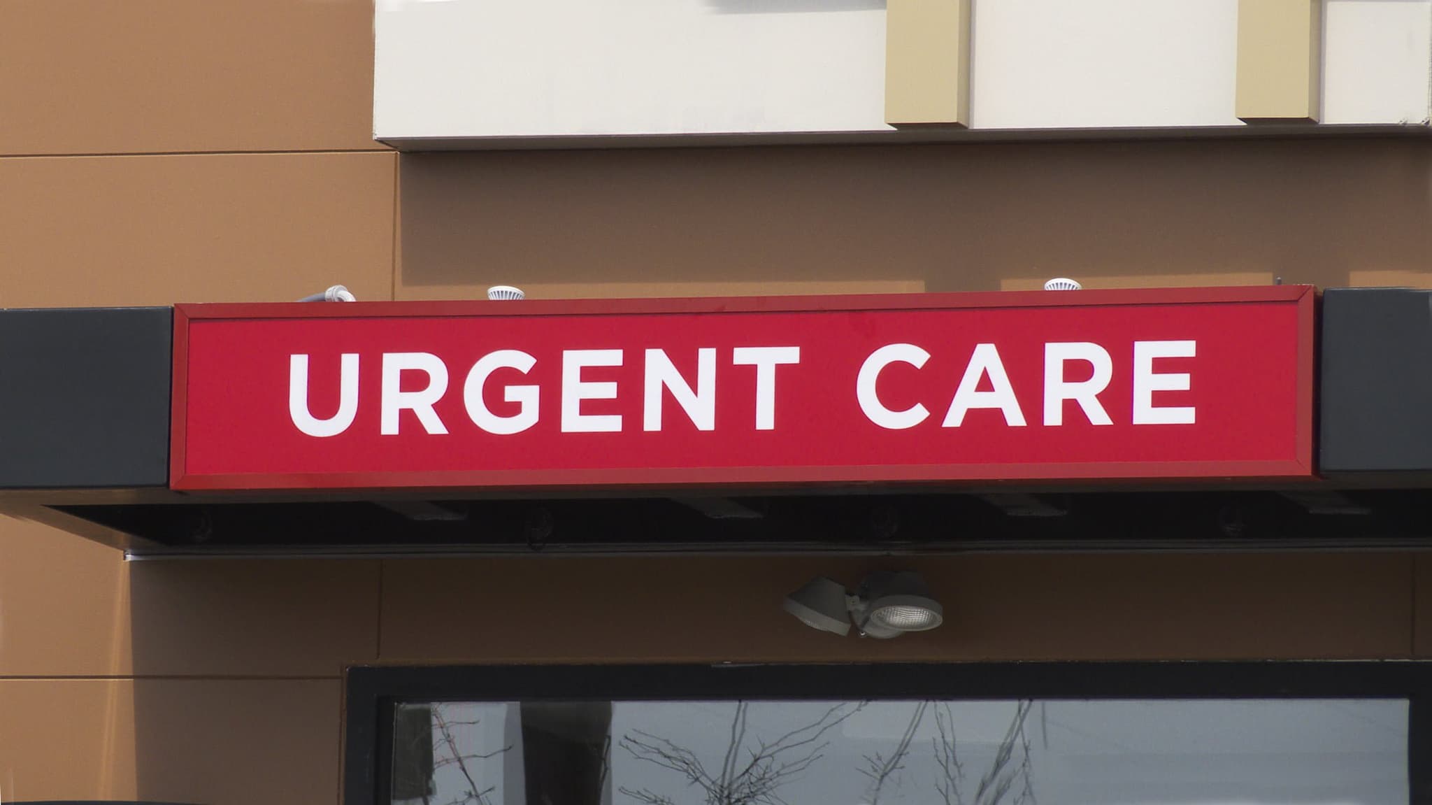 A closer exterior view of a red and white urgent care sign over an entrance. Urgent care centers are fast becoming an alternative to hospital ERs.