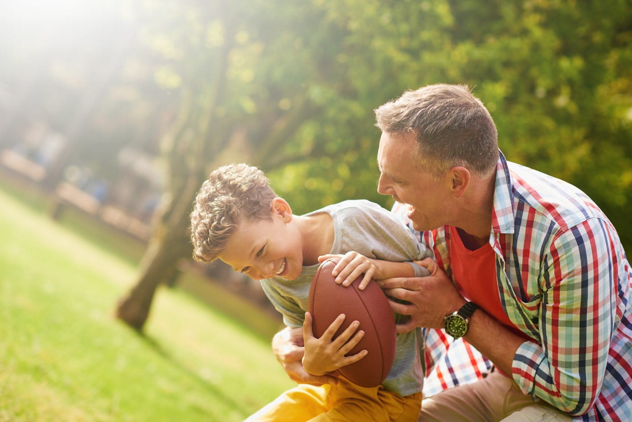 Picture of Shot of a father and son playing football in a park