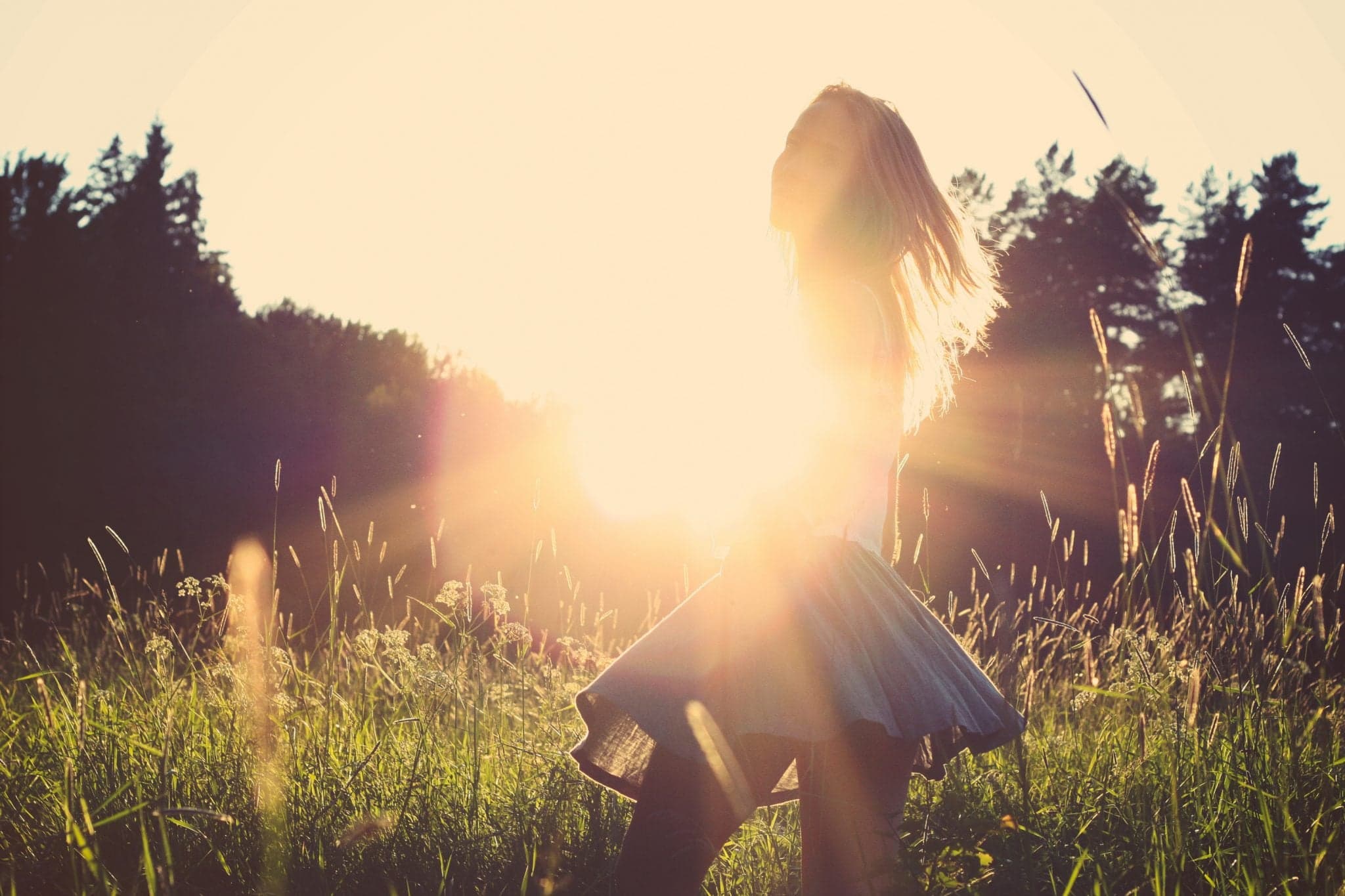 Picture of woman spinning in field with sunset