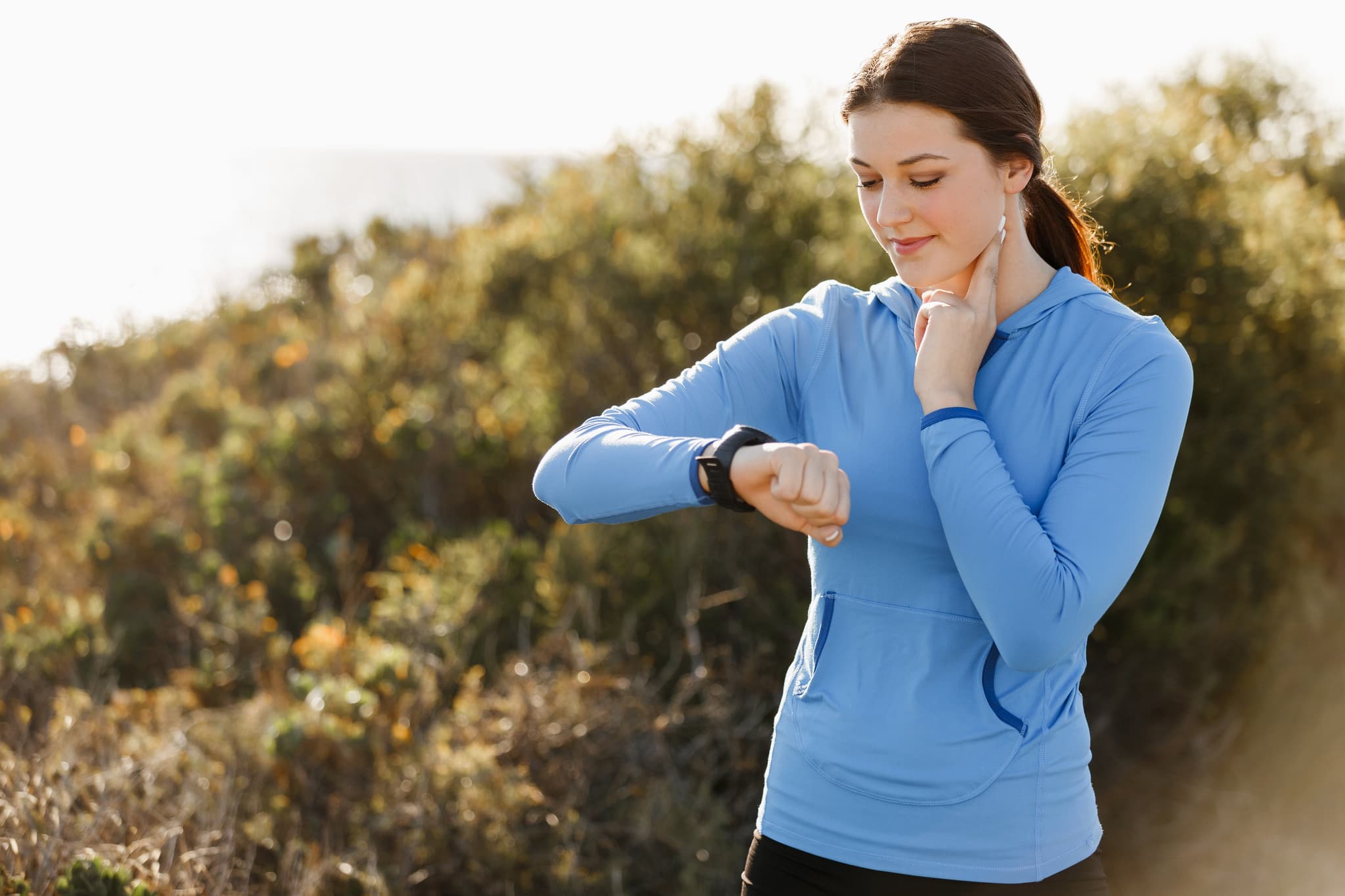 Young runner woman with heart rate monitor running on beach