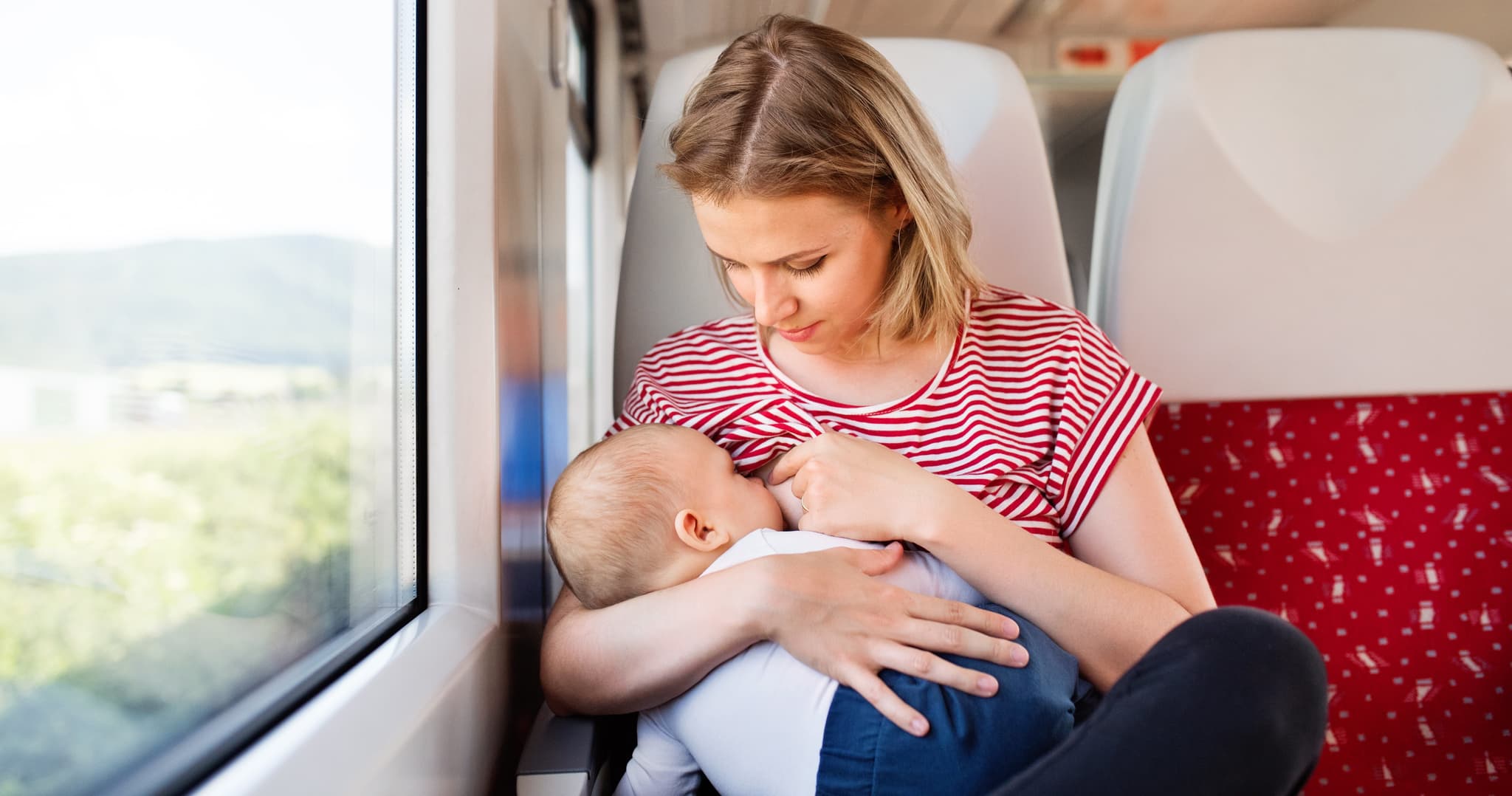 Young mother travelling with baby boy by train. Railway journey of a beautiful woman and her son.